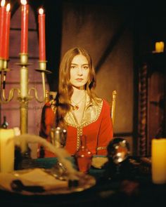 a woman sitting at a table with candles in the background