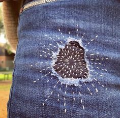 a person wearing blue jeans with white stitches on the side and a hole in the back