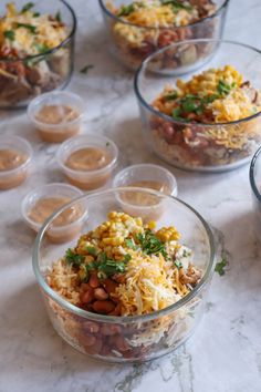 several bowls filled with food on top of a white marble counter topped with condiments