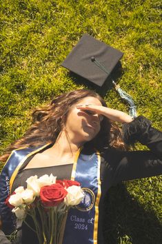 a woman laying in the grass with her graduation cap on