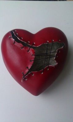 a red heart with metal rivets and a piece of wood sticking out of it