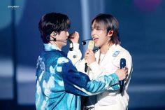 two young men standing next to each other holding microphones