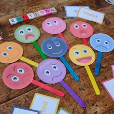 colorful paper lollipops with faces and words on them sitting on a wooden table