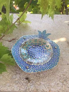 a blue and white bowl sitting on top of a stone table next to a plant