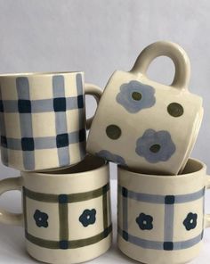 four coffee mugs stacked on top of each other with blue flowers painted on them