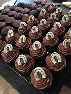 several chocolate cupcakes are on display in a bakery case with the letter q