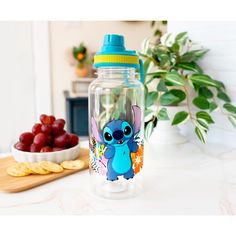 a glass water bottle sitting on top of a counter next to grapes and crackers