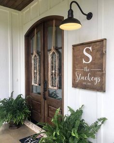 two potted plants sit on the front porch of a house with an entrance sign above it