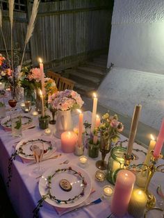 a table set with candles, plates and flowers