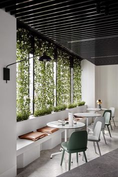 an empty restaurant with plants growing on the wall and tables in front of it,