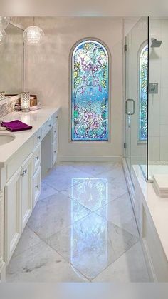 a bathroom with a large stained glass window in the shower and double sinks on both sides