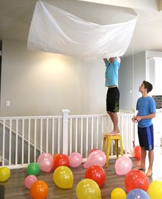 two boys are playing with balloons in the living room