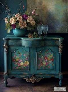 a blue painted cabinet with flowers and wine glasses on top