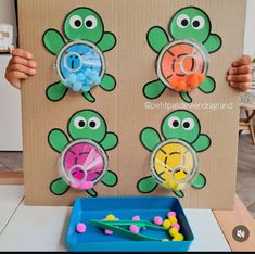 a child holding up a cardboard board with sea animals on it and some toys in front of it