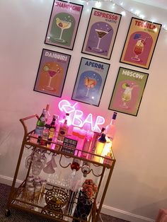 there is a bar cart with drinks on it in front of some posters and lights