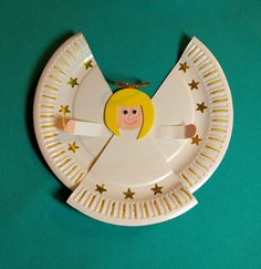 a paper plate with an angel design on the side and gold stars around it, sitting on a green surface