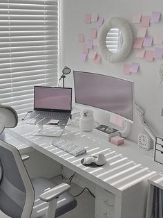 a white desk topped with two computer monitors and a laptop next to a window covered in pink sticky notes