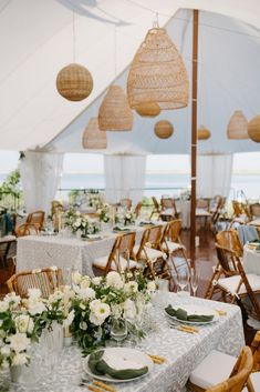 tables and chairs are set up in a tent for an outdoor wedding reception at the beach