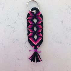 a pink and black keychain with a tassel hanging from it's end