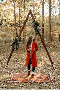 a woman standing in front of a teepee with wreaths on it and an orange blanket