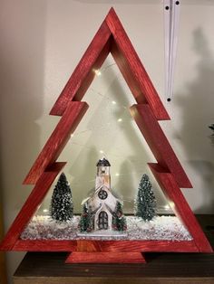 a christmas tree made out of wood with a church in the middle and lights on