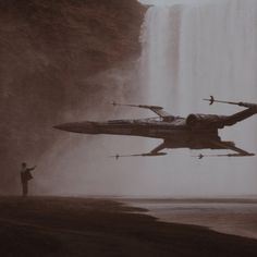 a man standing in front of a waterfall watching a star wars jet fly over it