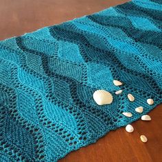 a blue knitted blanket with shells on it