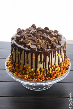 a cake with chocolate icing and candy candies on the top is sitting on a glass platter