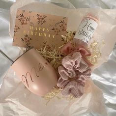 a happy birthday gift basket with coffee mug, candle and greeting card on white tissue paper