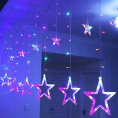 some stars hanging from the ceiling in front of a mirror with lights on it and one is purple