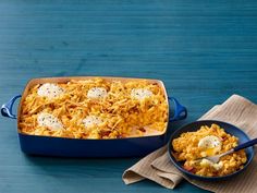 a blue casserole dish filled with macaroni and cheese on a wooden table