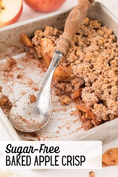 an apple crisp is in a baking dish with a spoon and some apples on the side