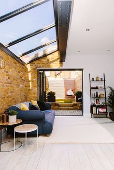 a living room filled with furniture next to a brick wall and skylight above it