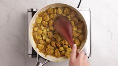 a person stirring food in a pot on the stove