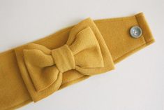 a yellow headband with a button on it and a bow tie around the band