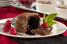 a piece of chocolate cake on a plate with raspberries