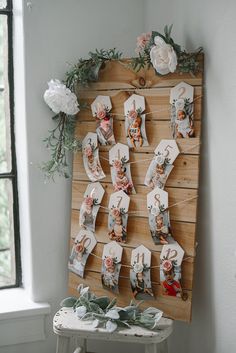 a wooden board with pictures on it and flowers hanging from the wall next to a small table