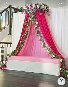 a bed covered in pink and white flowers on top of a wooden floor next to a stair case