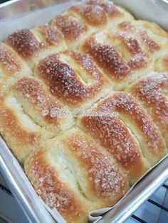 a baking pan filled with bread rolls covered in powdered sugar