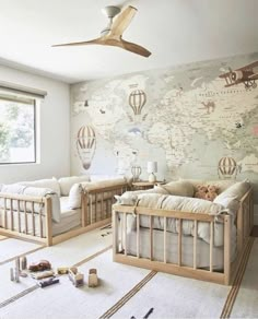 a baby's room with two cribs and a map on the wall