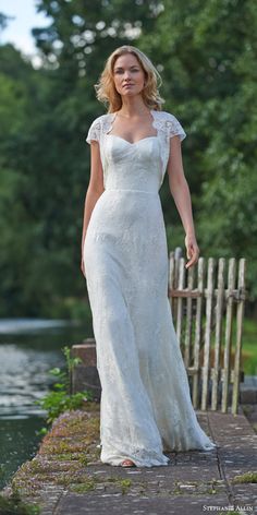 a woman in a white dress standing on a bridge