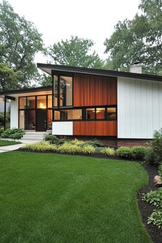 a modern house with grass and trees in the background