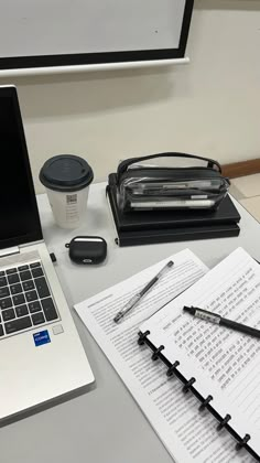 an open laptop computer sitting on top of a desk next to a cup of coffee