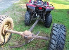 an atv is parked in the grass next to two large tires and one small wheel