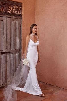 a woman in a white wedding dress with a veil on her head standing next to a door