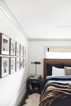 a bedroom with white walls and pictures on the wall