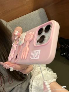 a woman holding up a pink phone case with dolls on it