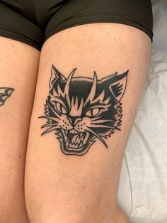 two black and white tattoos on the legs of women with cats'heads in them