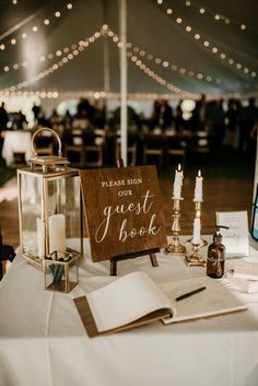 a sign that says guest book sitting on top of a table next to some candles