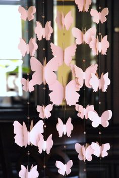 a wind chime with pink paper butterflies hanging from it's sides, in front of a window